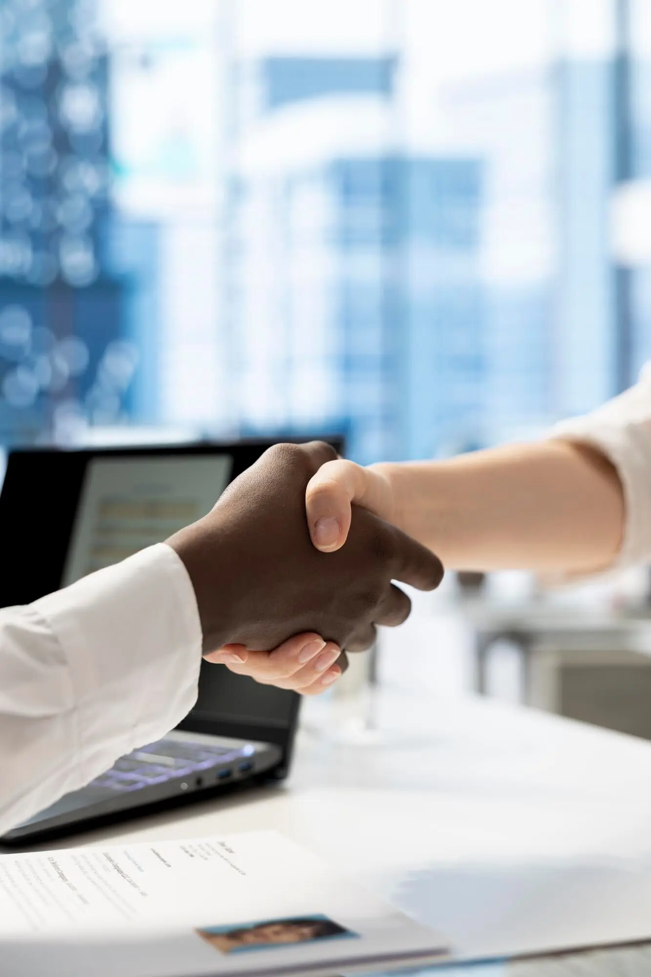 Крупный план: рекрутер в офисе приветствует соискателя рукопожатием.