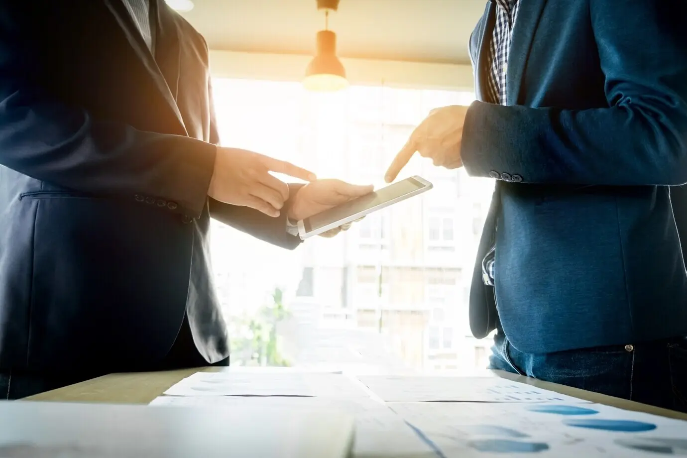 Процесс командной работы: команда молодых бизнес-менеджеров работает над новым проектом стартапа. Ноутбук на деревянном столе, печатают на клавиатуре, отправляют сообщения, анализируют графики и планы.